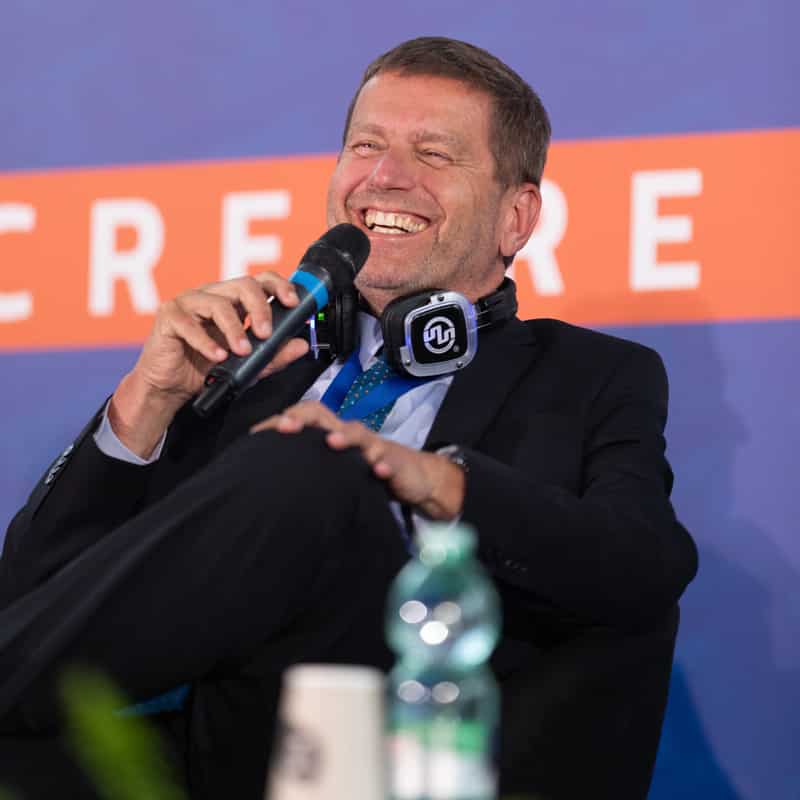 Audio per Conferenze Smiling speaker with a microphone and headphones at a conference
