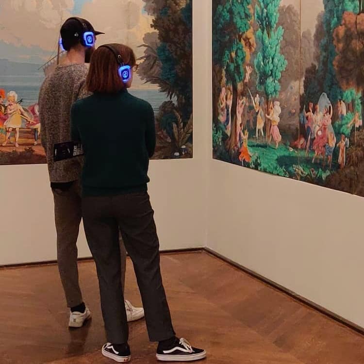 Palazzo del Louvre Visitors with wireless headphones in front of paintings at the Louvre