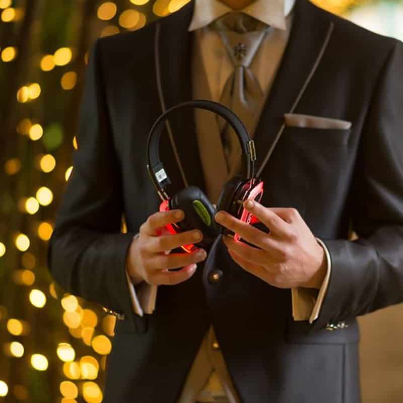 matrimonio Groom in a sharp suit holding silent disco headphones